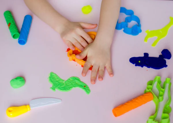 child hands playing colorful clay